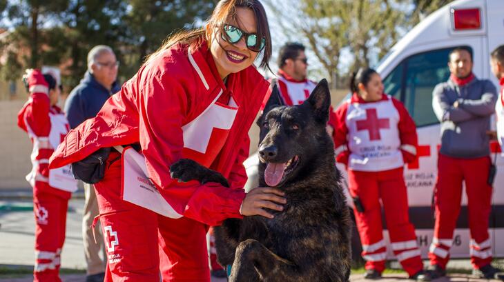 A volunteer from the Mexican Red Cross poses with a dog while commemorate Happiness Day.